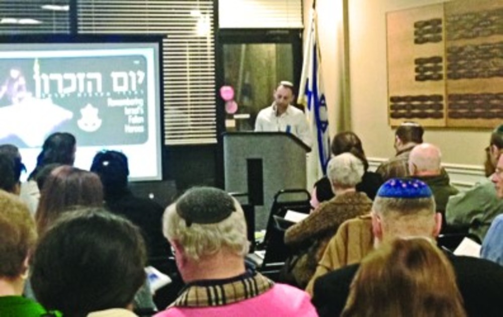 Elad Vilk leads participants in the Yom HaZikaron program in songs and readings to commemorate those  who gave their lives for Israel. /Jewish Alliance Staff